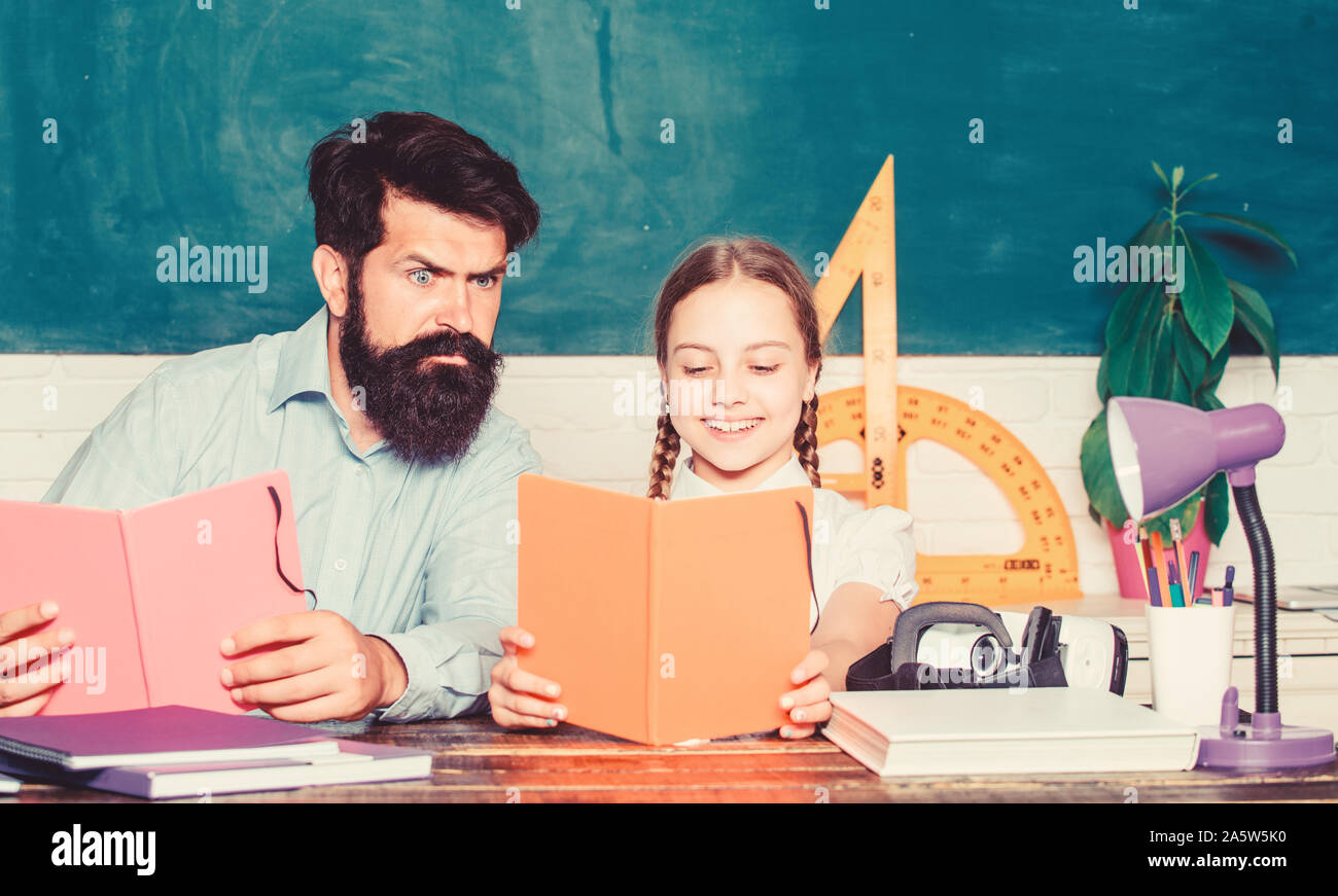 Concentrated on studying. small girl child with bearded teacher man in classroom. daughter study with father. Teachers day. back to school. Private teaching. knowledge. Home schooling. private lesson. Stock Photo