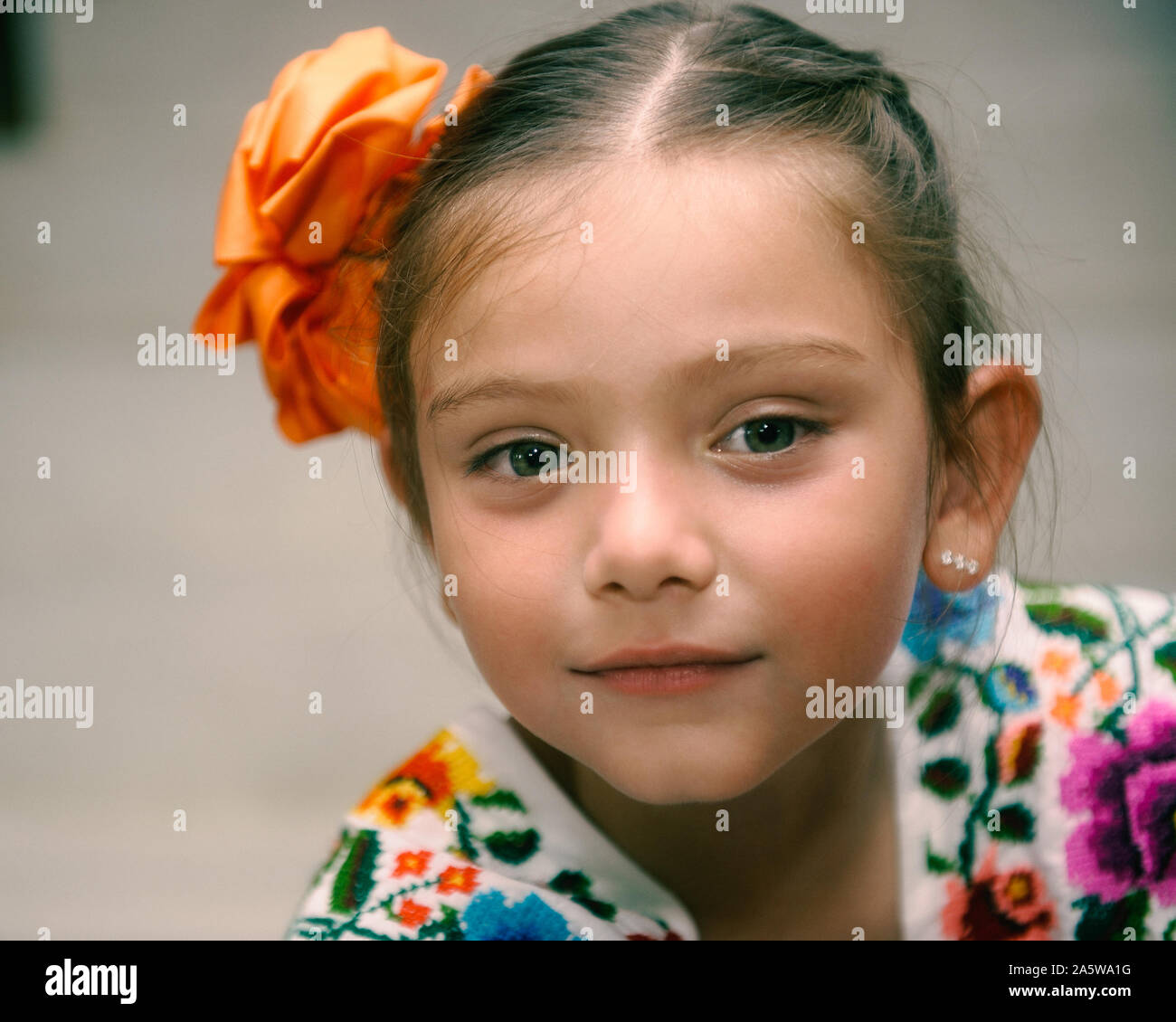 Merida, Yucatan, Mexico - May 10, 2015: Blue-eyed, 7 years old Mexican girl wearing regional Mayan dress (Huipil) and a fabric flower on her hair. Stock Photo
