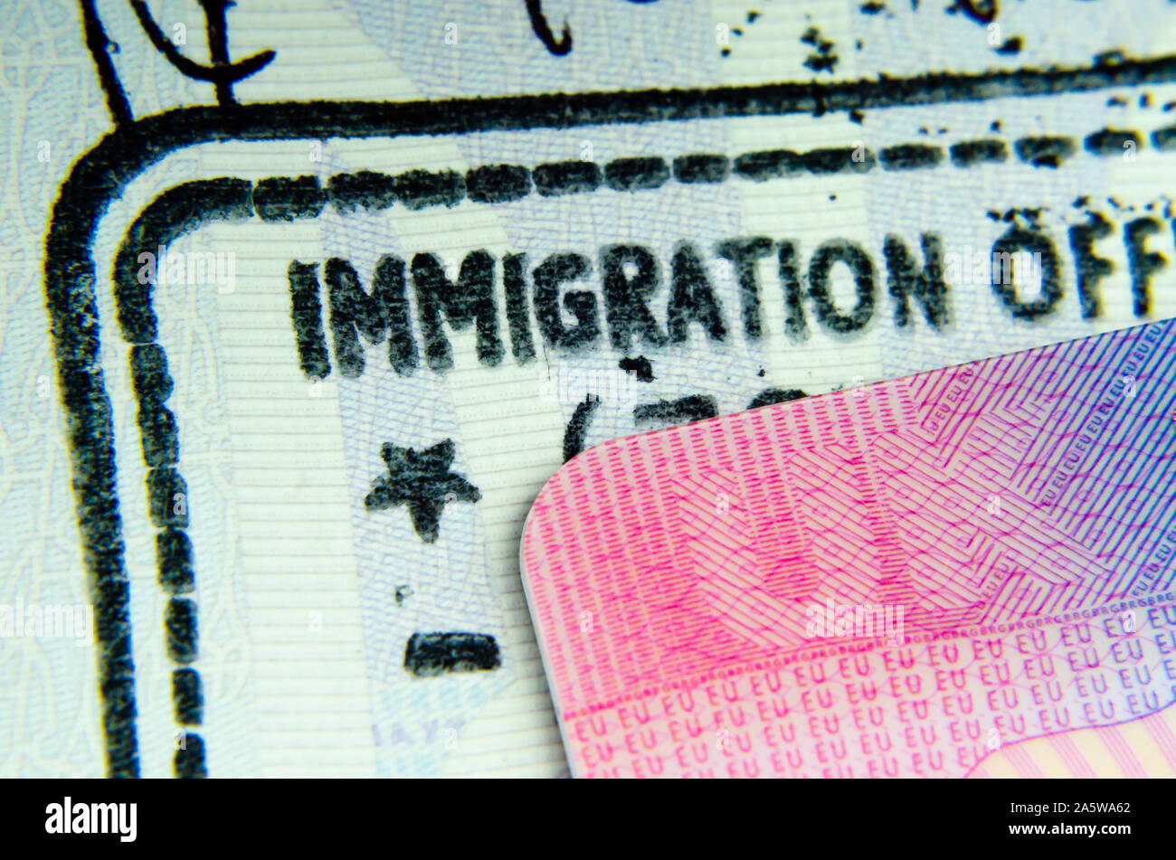UK BRP Tier 2 visa card on top of immigration stamp in passport where only letters 'IMMIGRATION OFF' visible from the  'IMMIGRATION OFFICER' phrase. Stock Photo