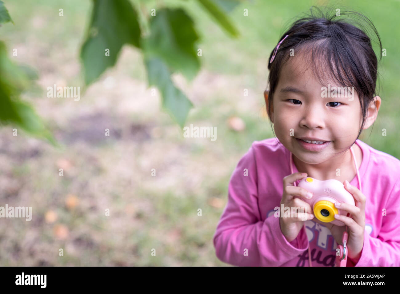 Asian little girl holding a plastic camera toy Stock Photo
