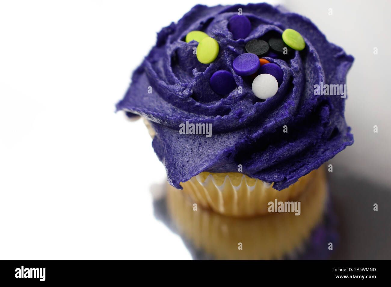 Closeup of Halloween Cupcake Iced with Purple Frosting and Multicolored Confetti Dots Stock Photo