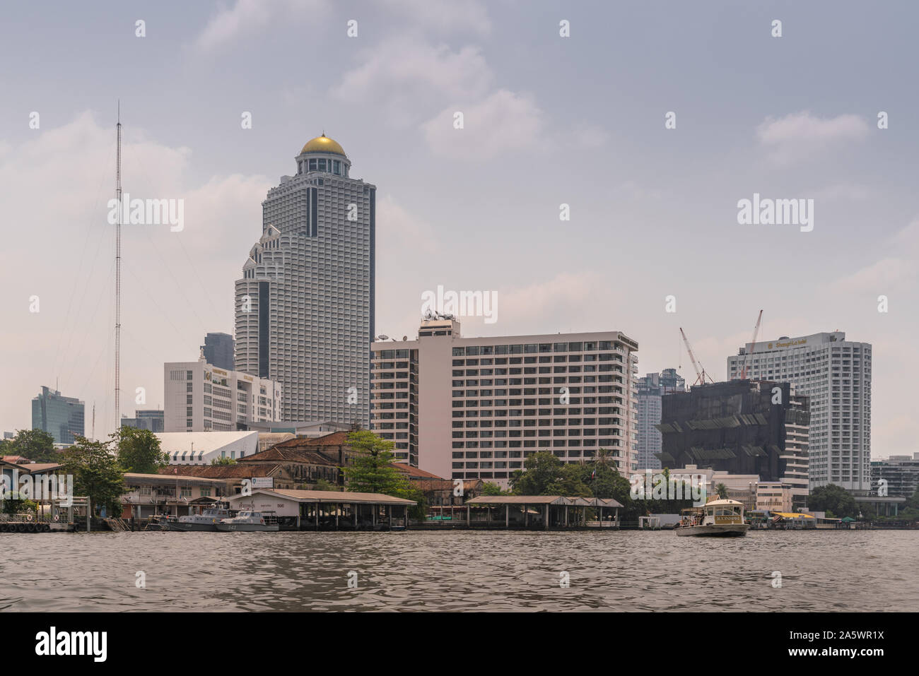 Bangkok city, Thailand - March 17, 2019: Chao Phraya River. Three hotel towers and another one under construction: State Tower with golden dome housin Stock Photo