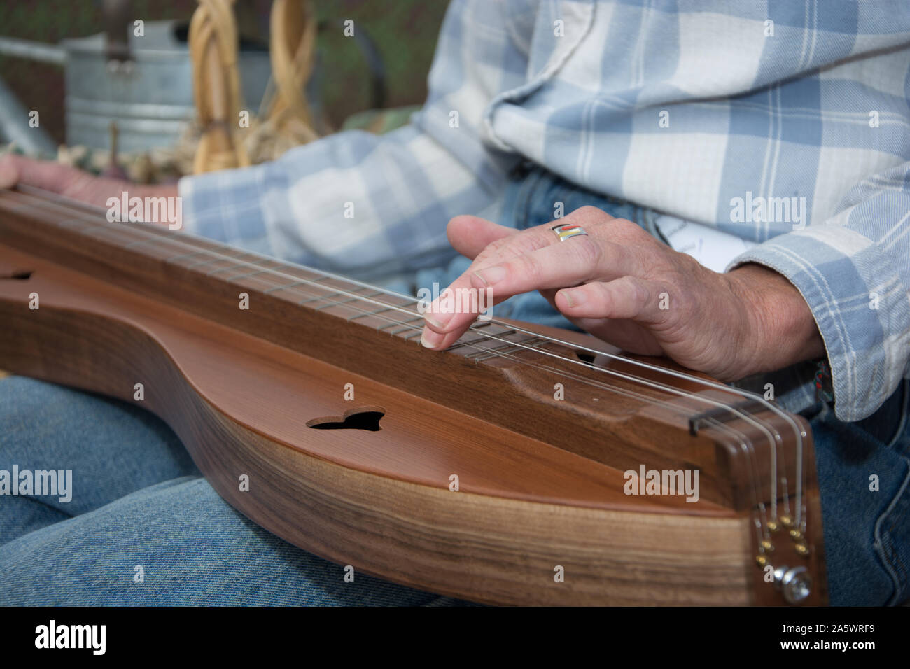 A woman in western attire learns to play the dulcimer on the bed of a flat pick up truck in a rural area at harvest time. Stock Photo