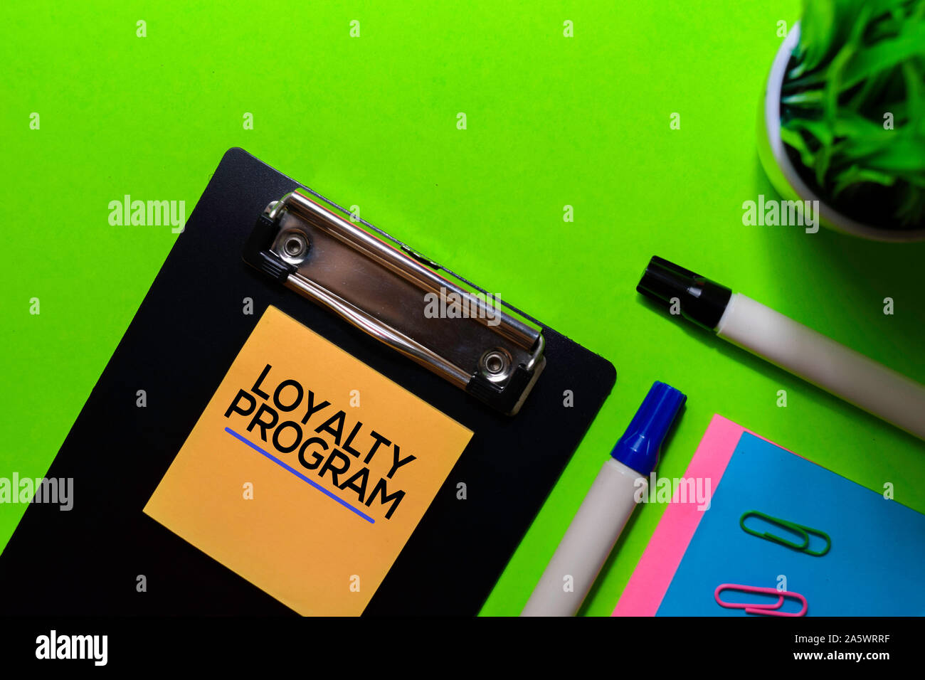 Loyalty Program write on sticky notes. Isolated on green table background Stock Photo