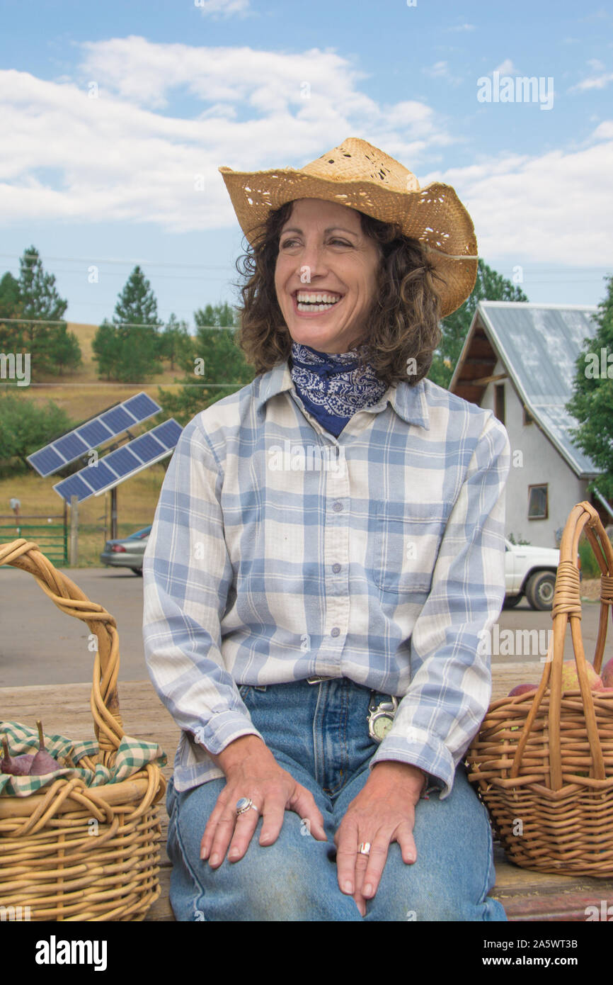 A woman in western attire sells farm fresh produce in wicker baskets off the back of a flat bed pick up truck. Stock Photo