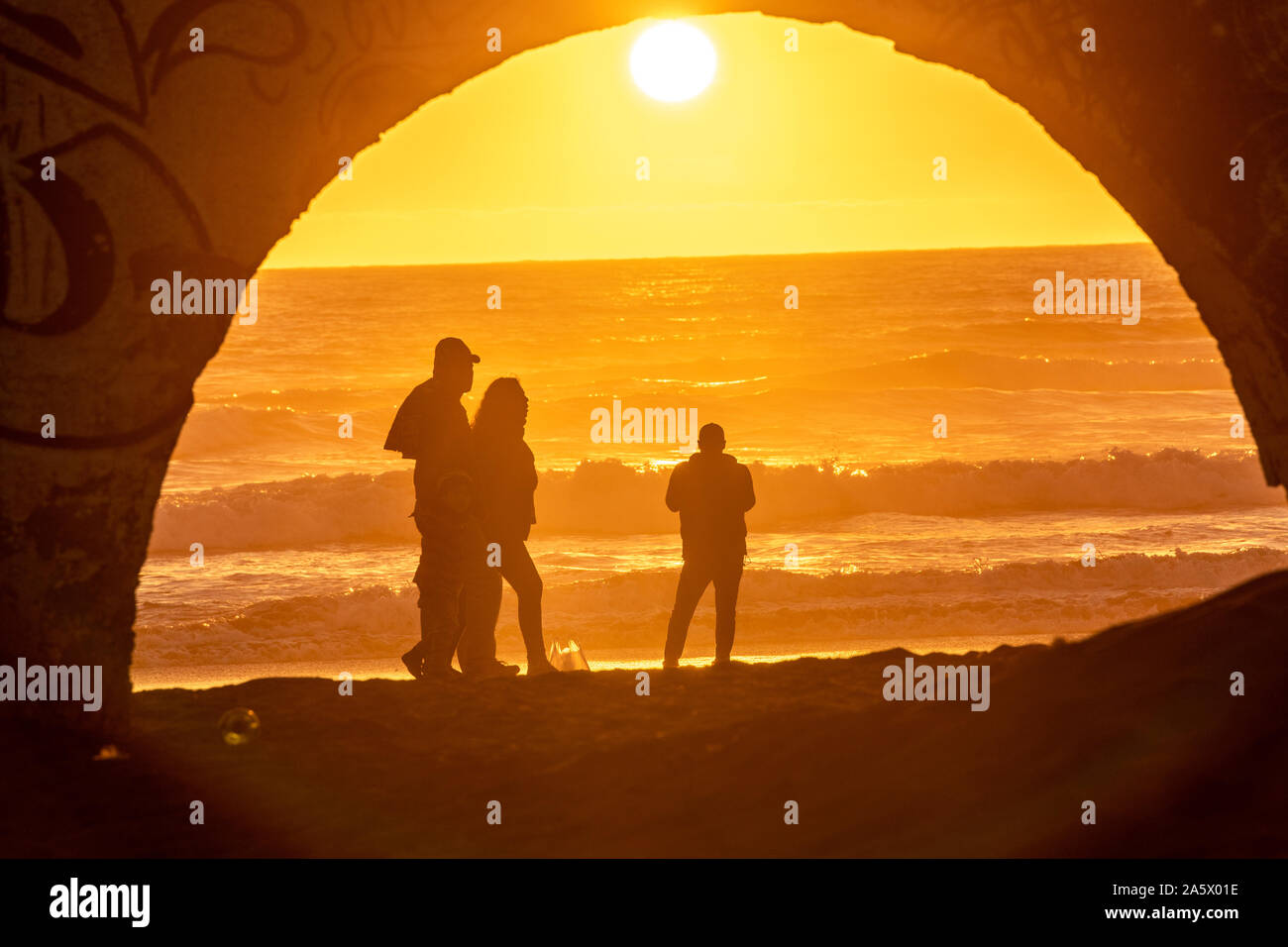 Beachgoers are silhouetted by the fierce orange sunset, La Serena, Chile. Stock Photo