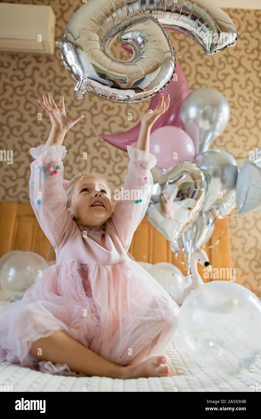 Indoor shot of pretty joyful little girl with blonde hair celebrating 6 years old birthday with balloons wear fashionable dress have excited Stock Photo Alamy