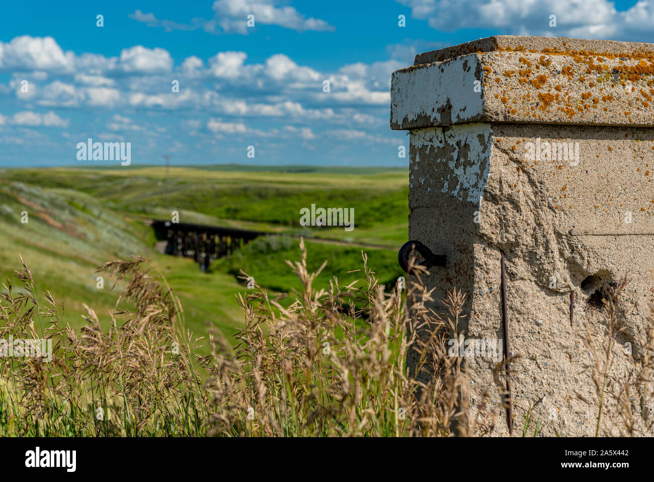 Pillar from the historic concrete bridge in Scotsguard, SK with a wooden railway tressle in the background Stock Photo