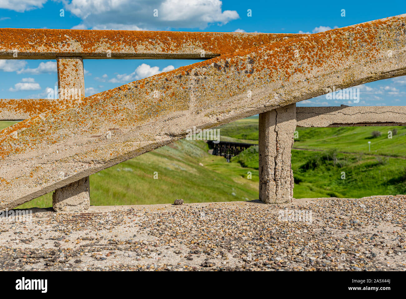 Lichen-covered arch from the concrete bridge in Scotsguard, SK with a historic railway tressle in the background Stock Photo