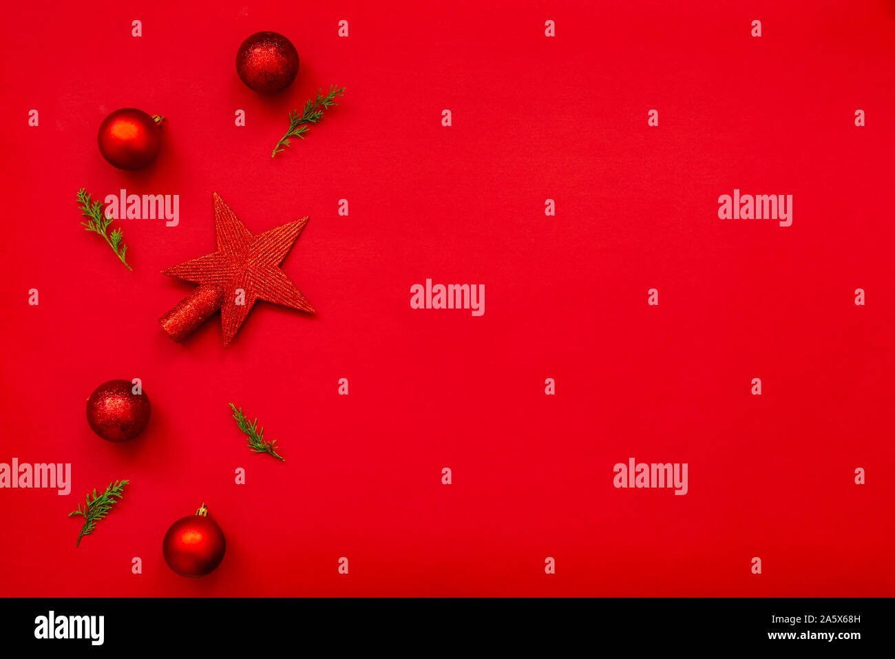 Christmas background - flat lay of red christmas balls, pine cones and fir branches over red background. Copy space. Stock Photo