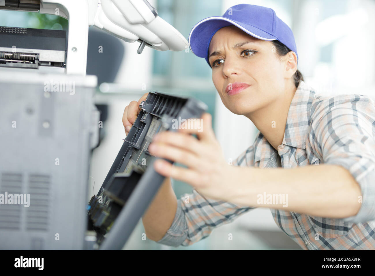 young woman fixing a printer Stock Photo