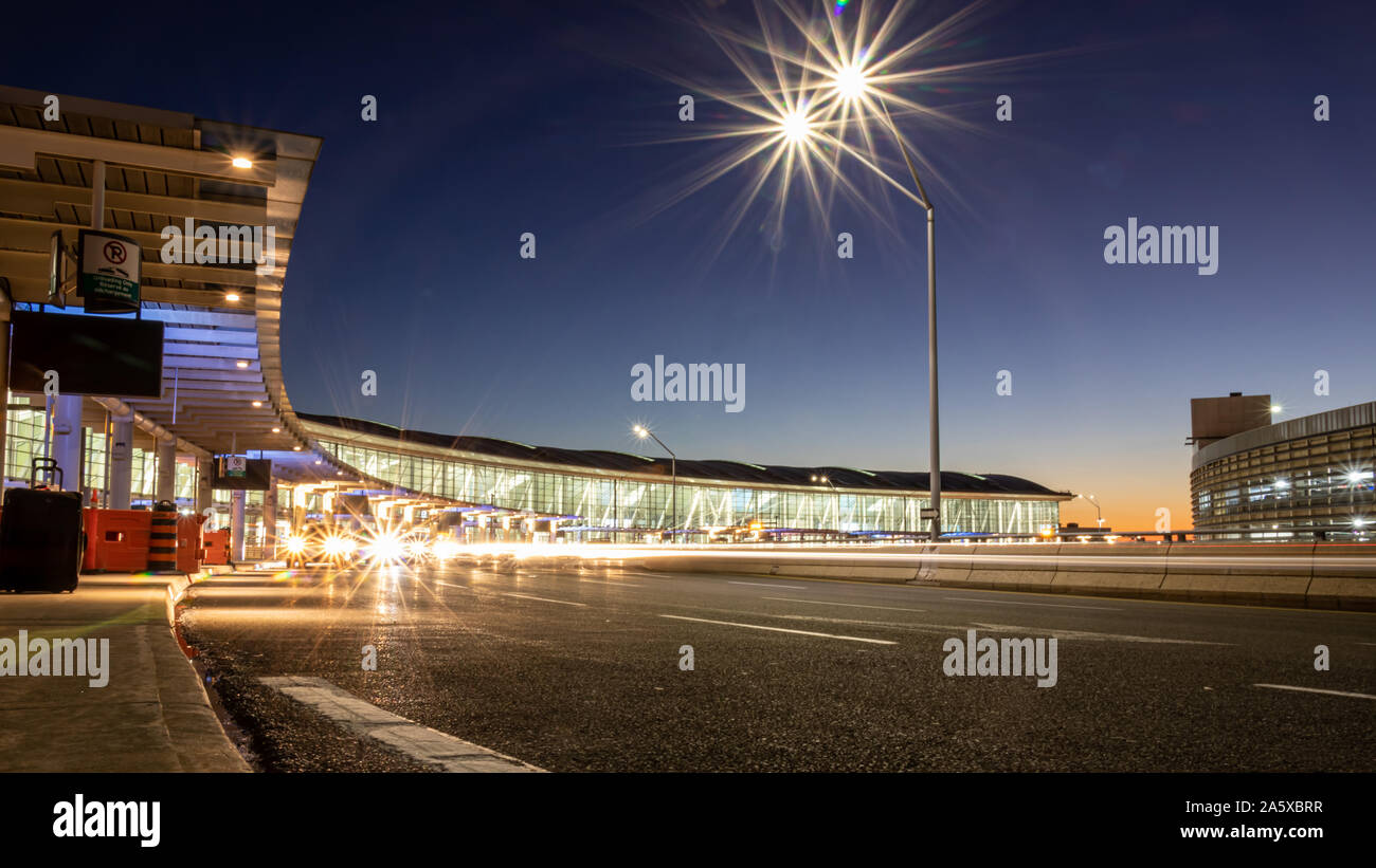 Long exposure of cars at and passing by at the upper level of Terminal 1 at Toronto Pearson Intl. Airport during a beautiful sunset. Stock Photo