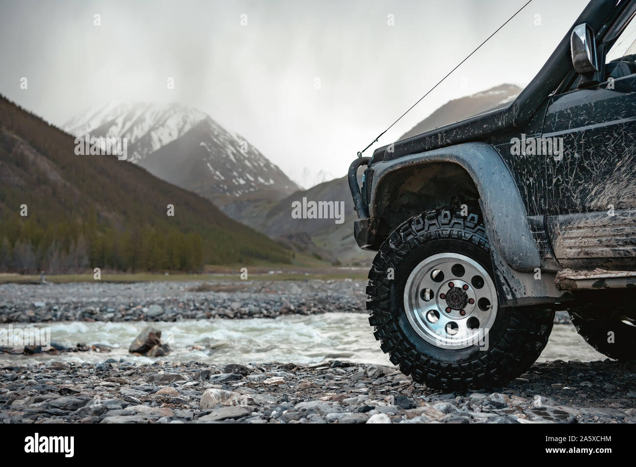 Big extreme offroad ready car wheel against mountains and river Stock Photo