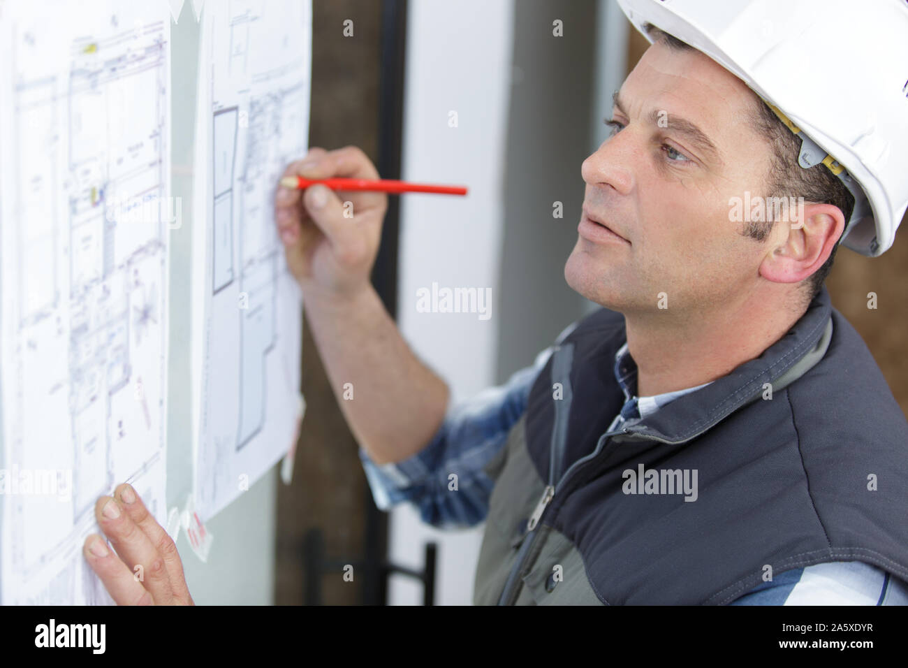 smart engineer in helmet drawing with pencil a plan Stock Photo - Alamy