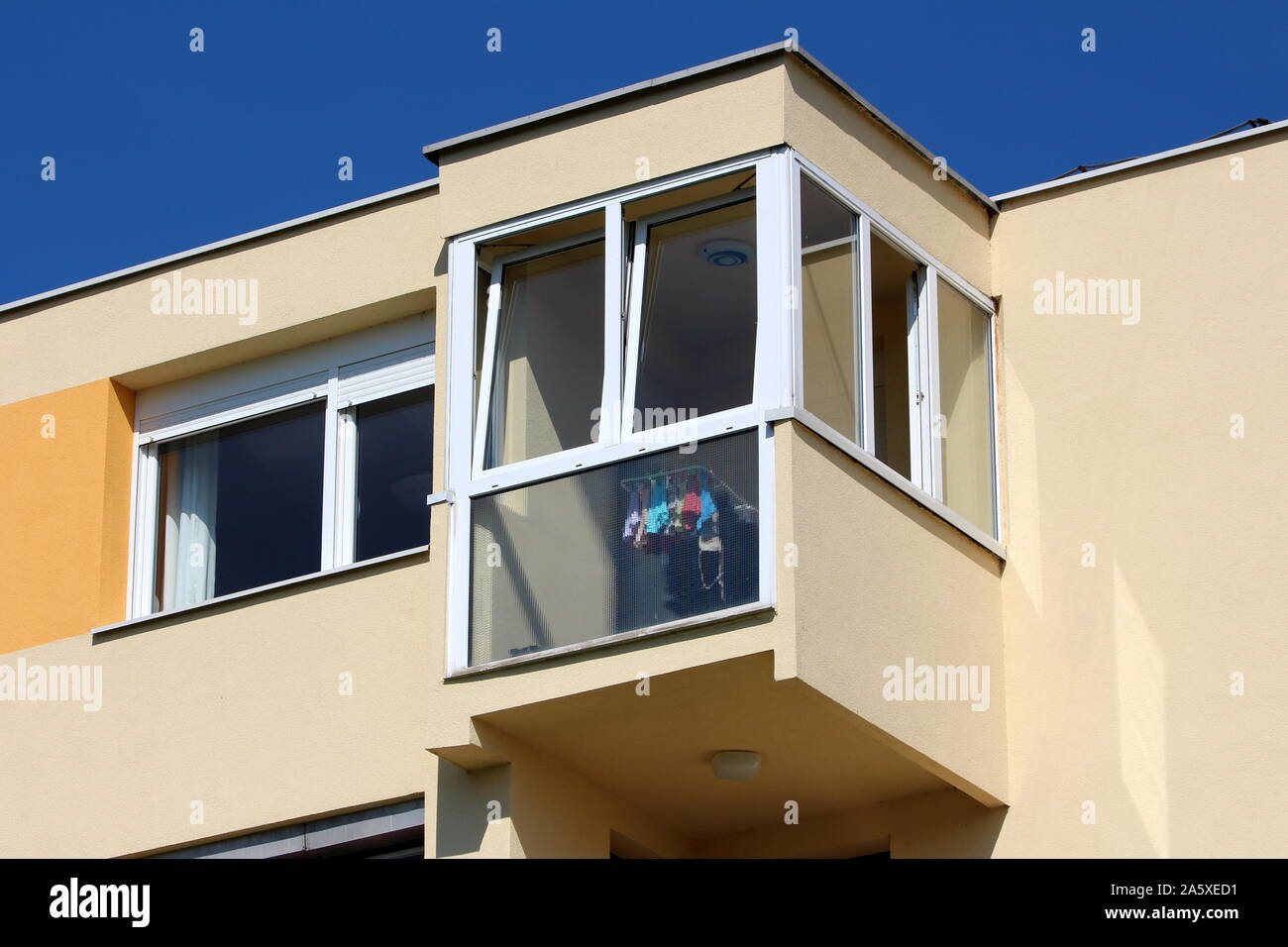 Corner balcony with large glass surface on top of colorful renovated apartment building on warm sunny summer day Stock Photo