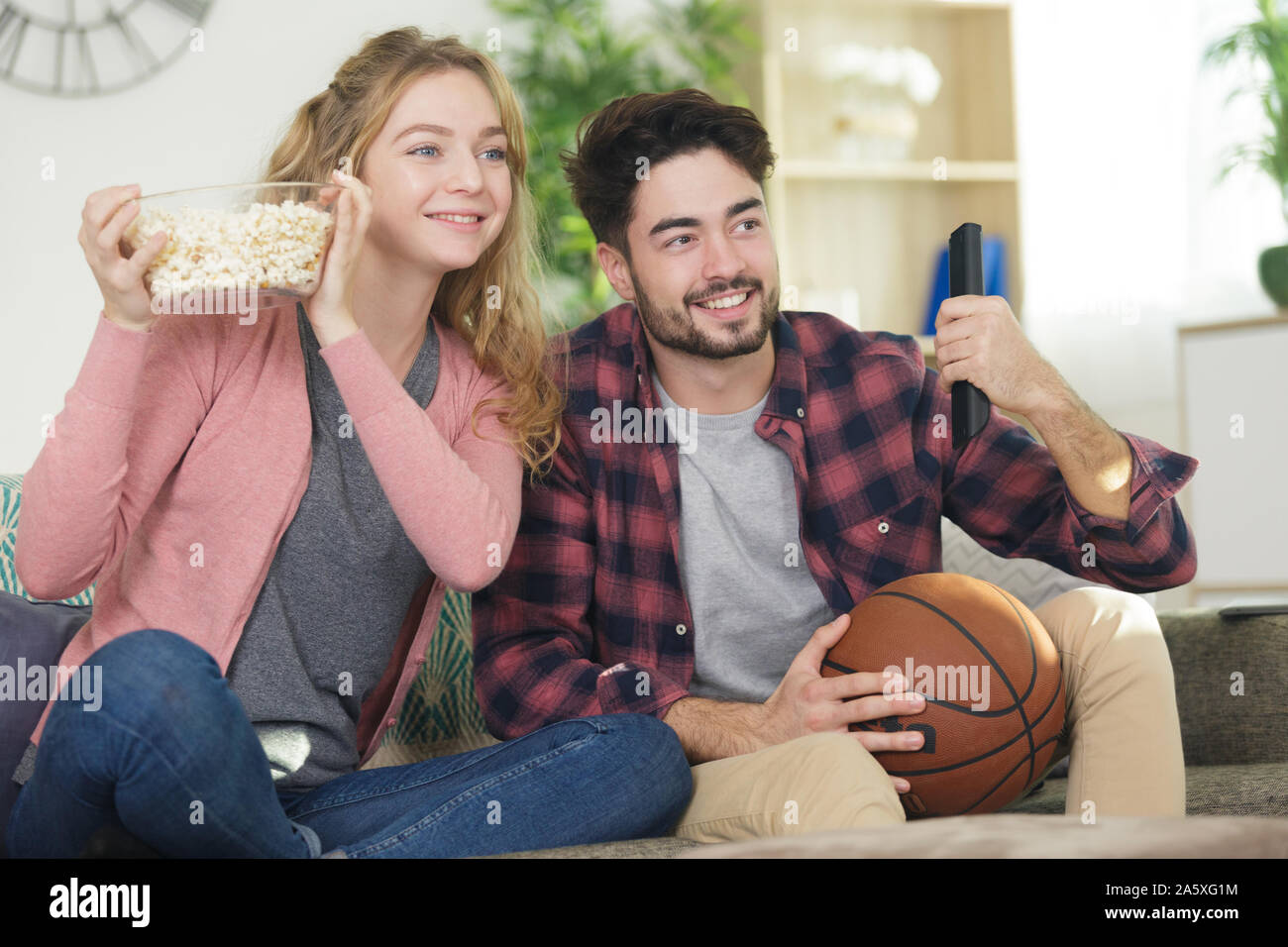young couple watching basketball on tv Stock Photo Alamy
