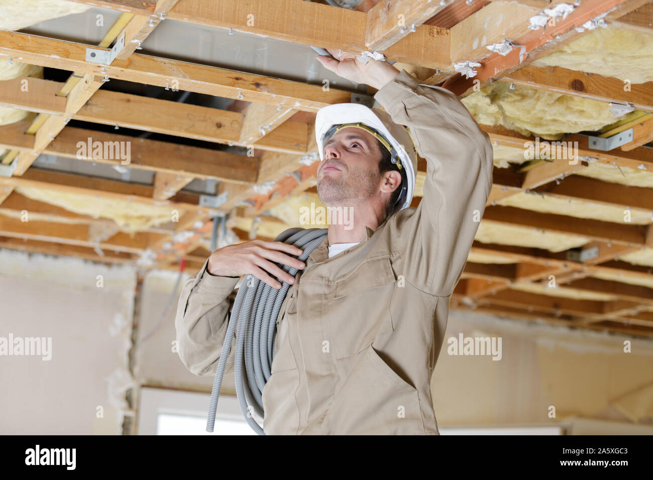 male builder with reel of cable on his shoulder Stock Photo