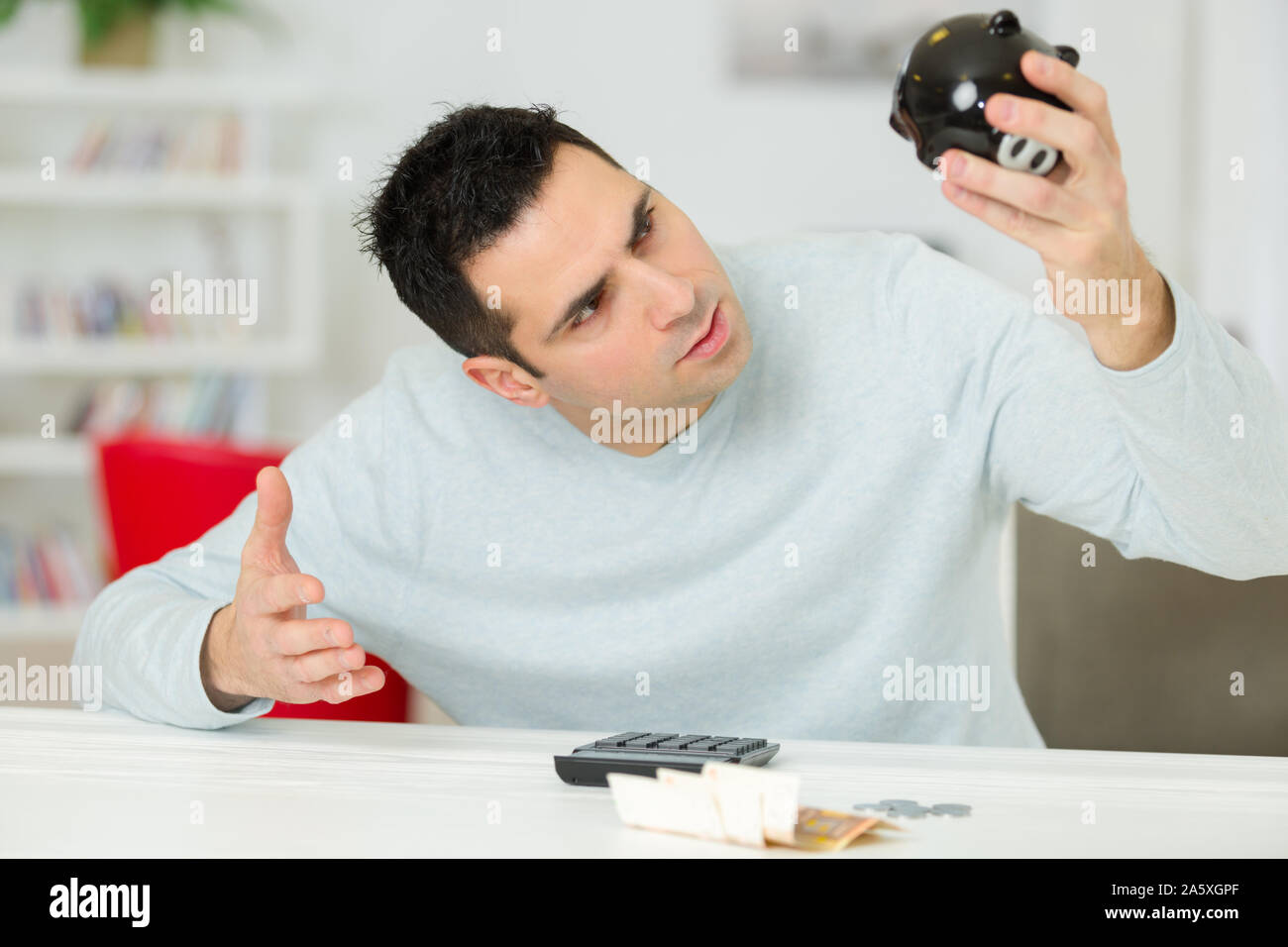 young man looking in desperation at his empty piggy bank Stock Photo ...