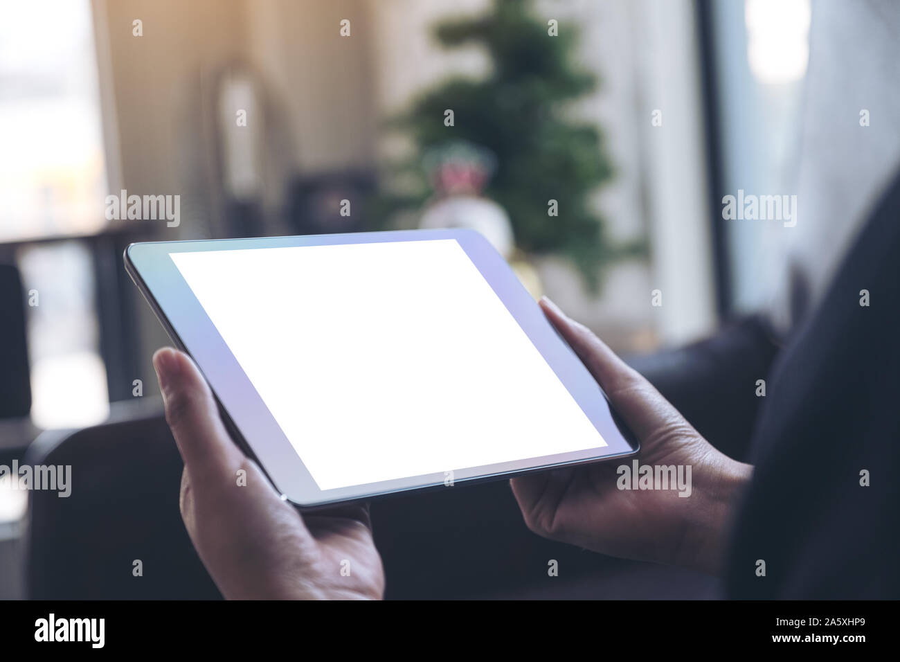 Mockup image of hands holding black tablet pc with blank white desktop ...
