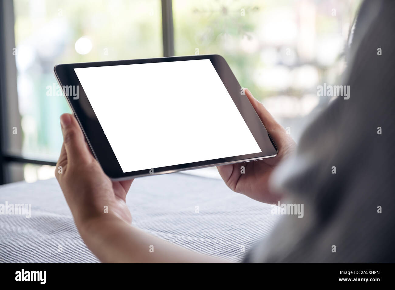 Mockup image of hands holding black tablet pc with blank white desktop ...