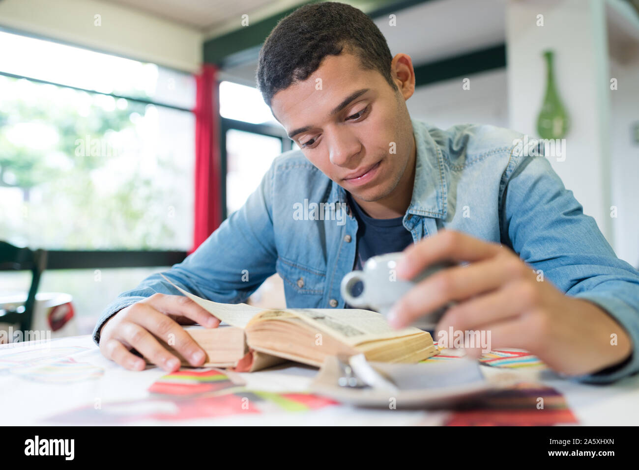 young man readying a book while drinking coffee Stock Photo - Alamy