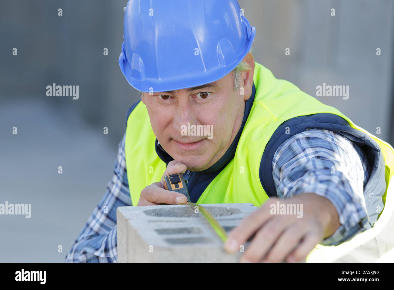 construction worker is working with cement block measurement Stock