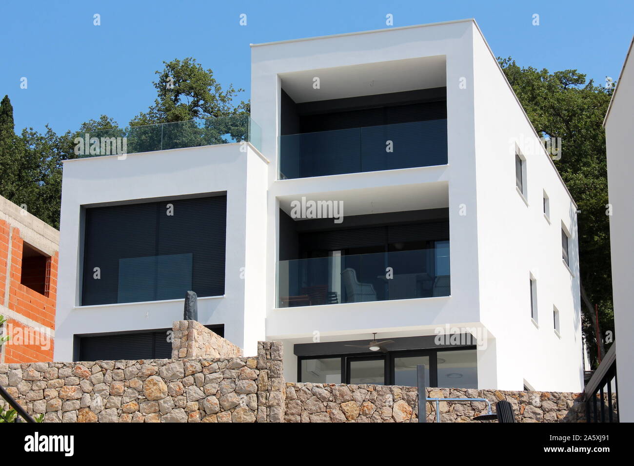 New modern apartment building with white facade and glass balcony fence ...