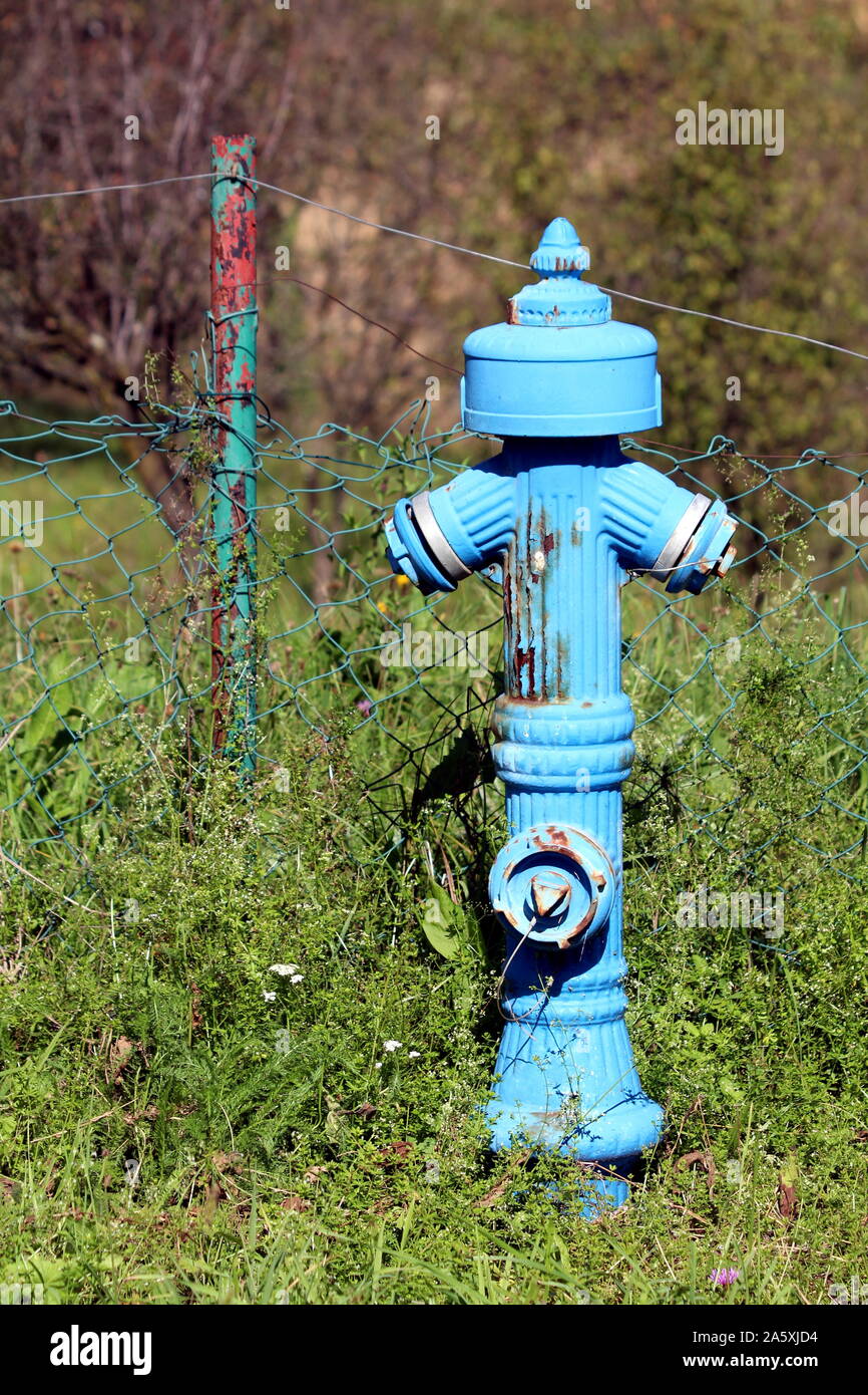Old partially rusted vintage light blue metal fire hydrant in front of