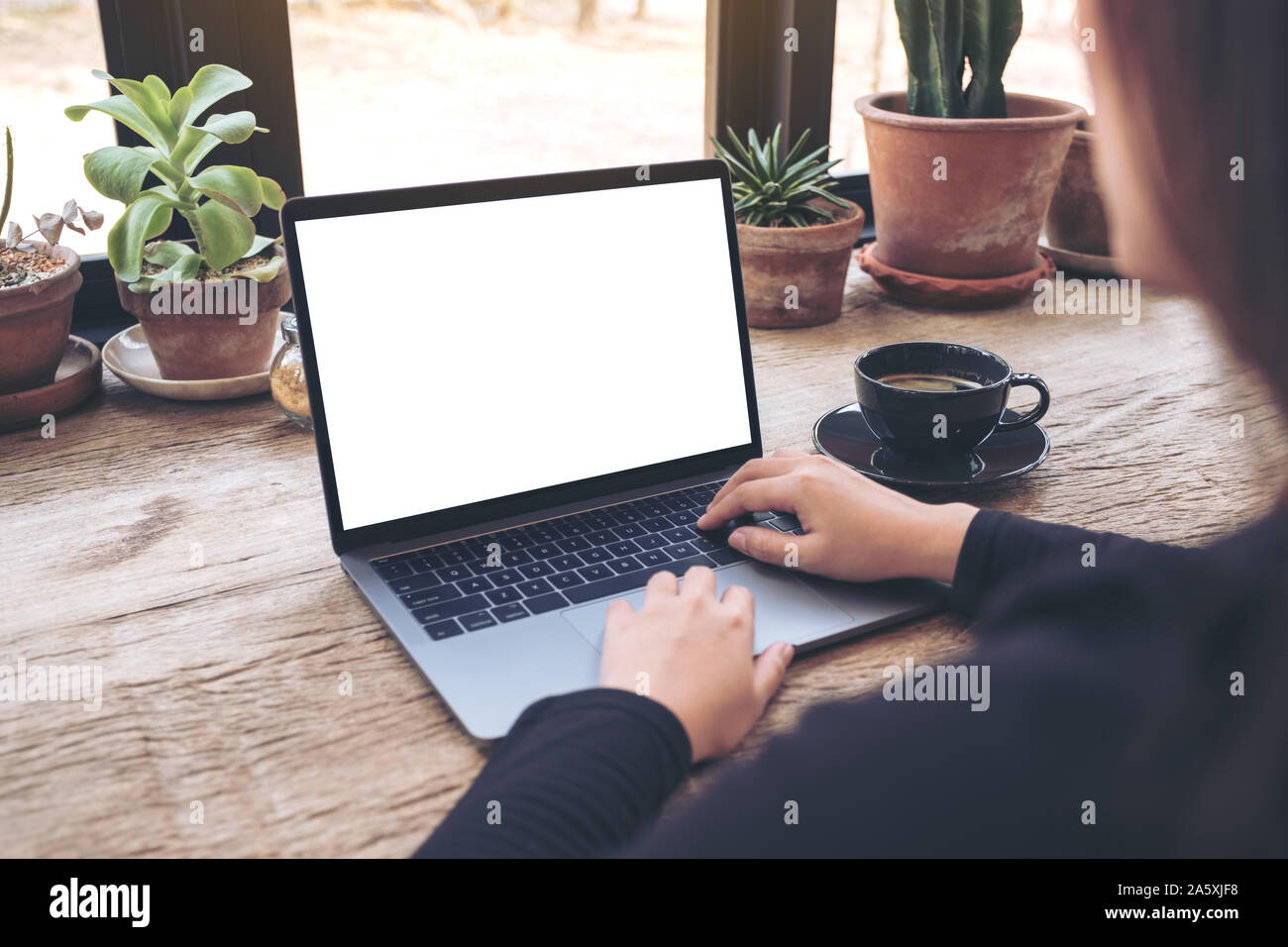 Mockup image of woman using and typing on laptop with blank white ...