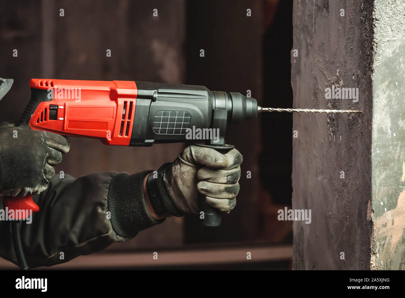 Man at work drilling hole with big driller to a wall Stock Photo