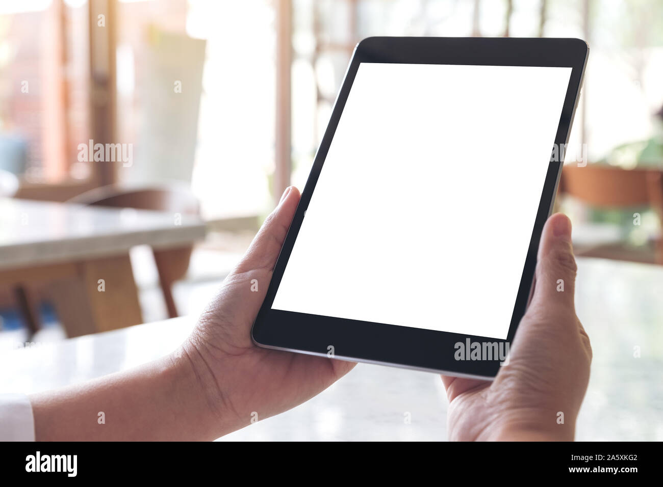 Mockup image of hands holding black tablet pc with blank white desktop ...