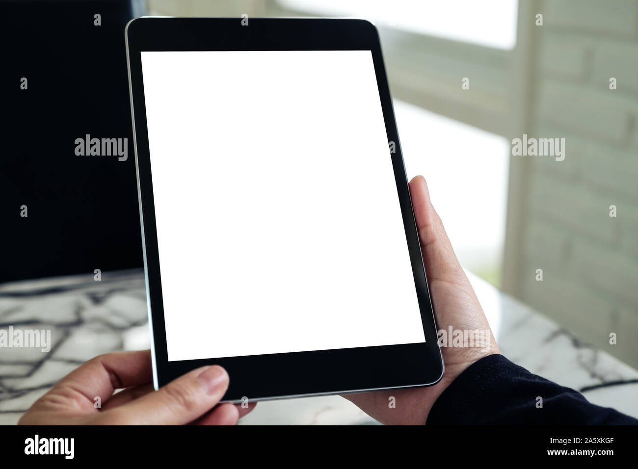 Mockup image of hands holding black tablet pc with blank white desktop ...