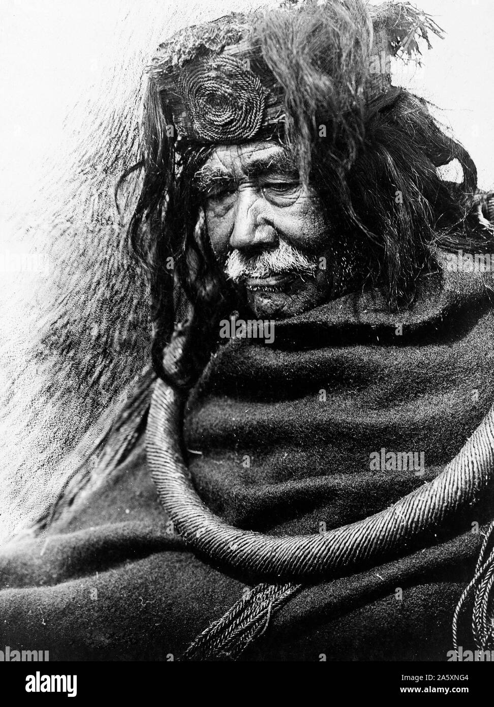Edward S. Curits Native American Indians - Half-length portrait of Nakoaktok man, facing left, wearing cedar root ceremonial loop ca. 1910 Stock Photo