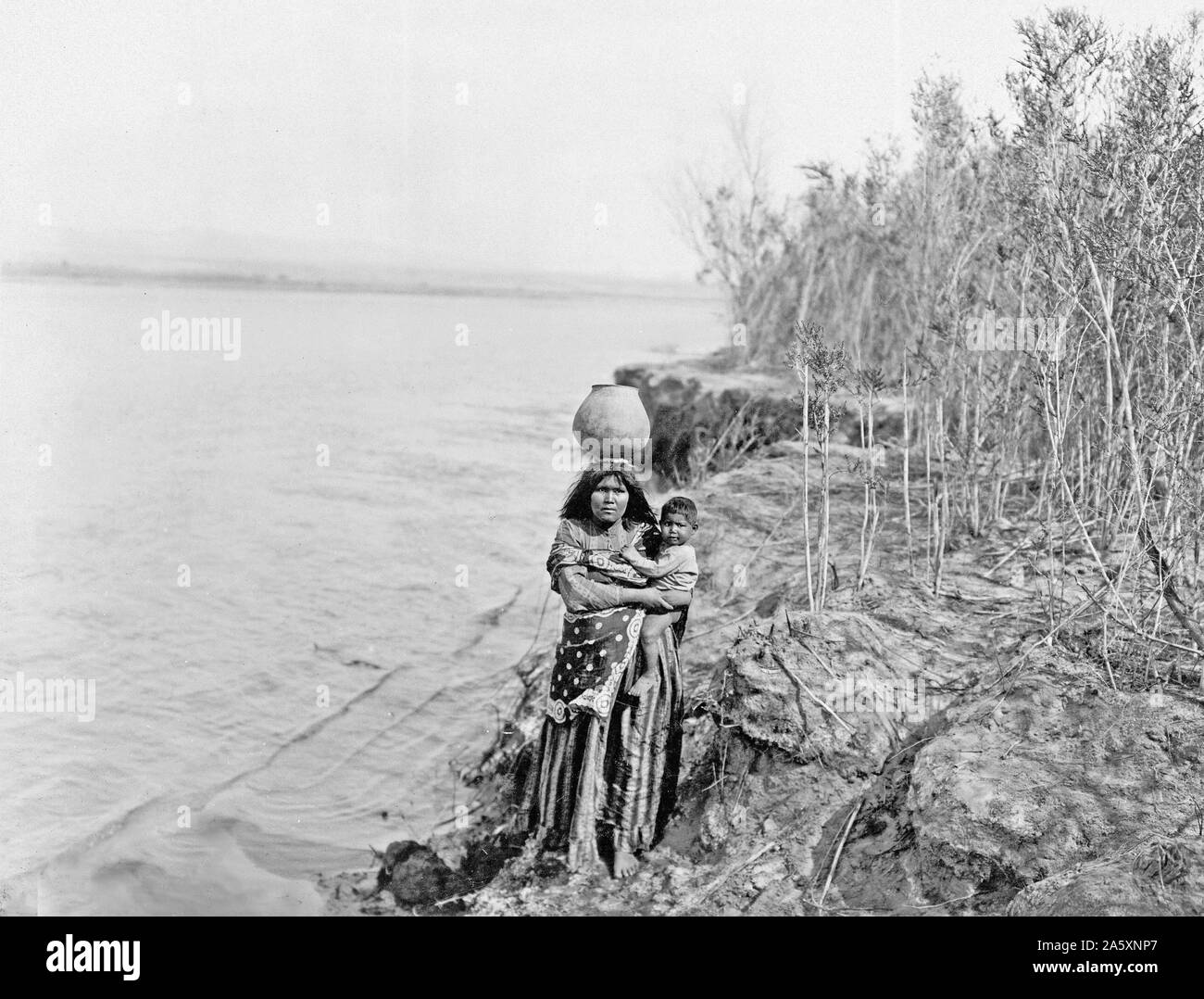 Edward S. Curits Native American Indians - Mohave Indian woman carrying water on her head and holding child ca. 1903 Stock Photo