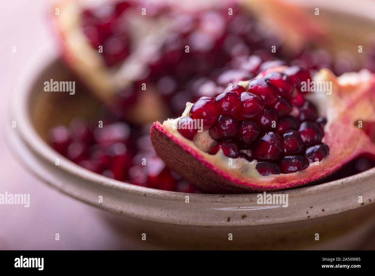 Closeup of pomegranate slices and seeds in a ceramic bowl. Stock Photo
