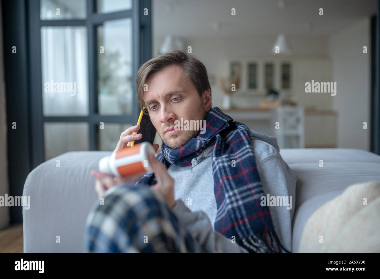 Sick blue-eyed man calling his doctor while having high fever Stock Photo