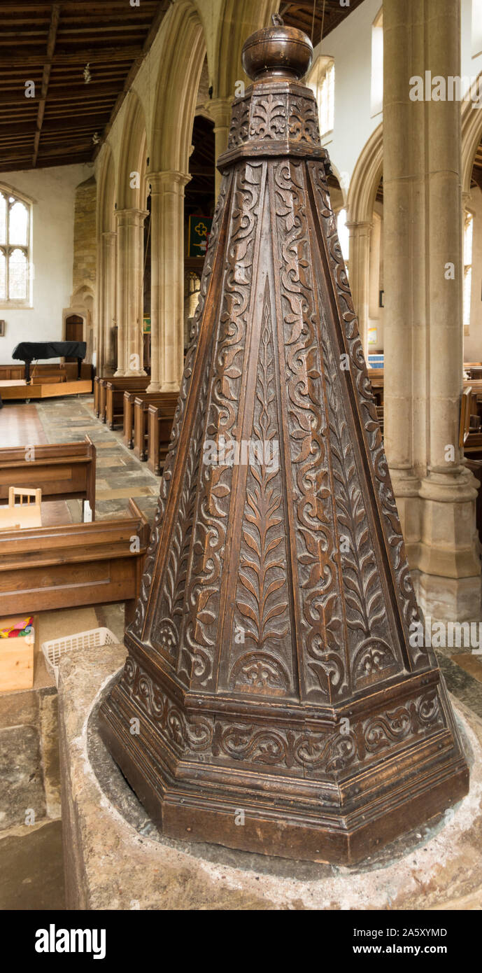 Old stone church font with fancy, ornate carved oak wood cover, St Andrews Church, Lyddington, Rutland, England UK Stock Photo