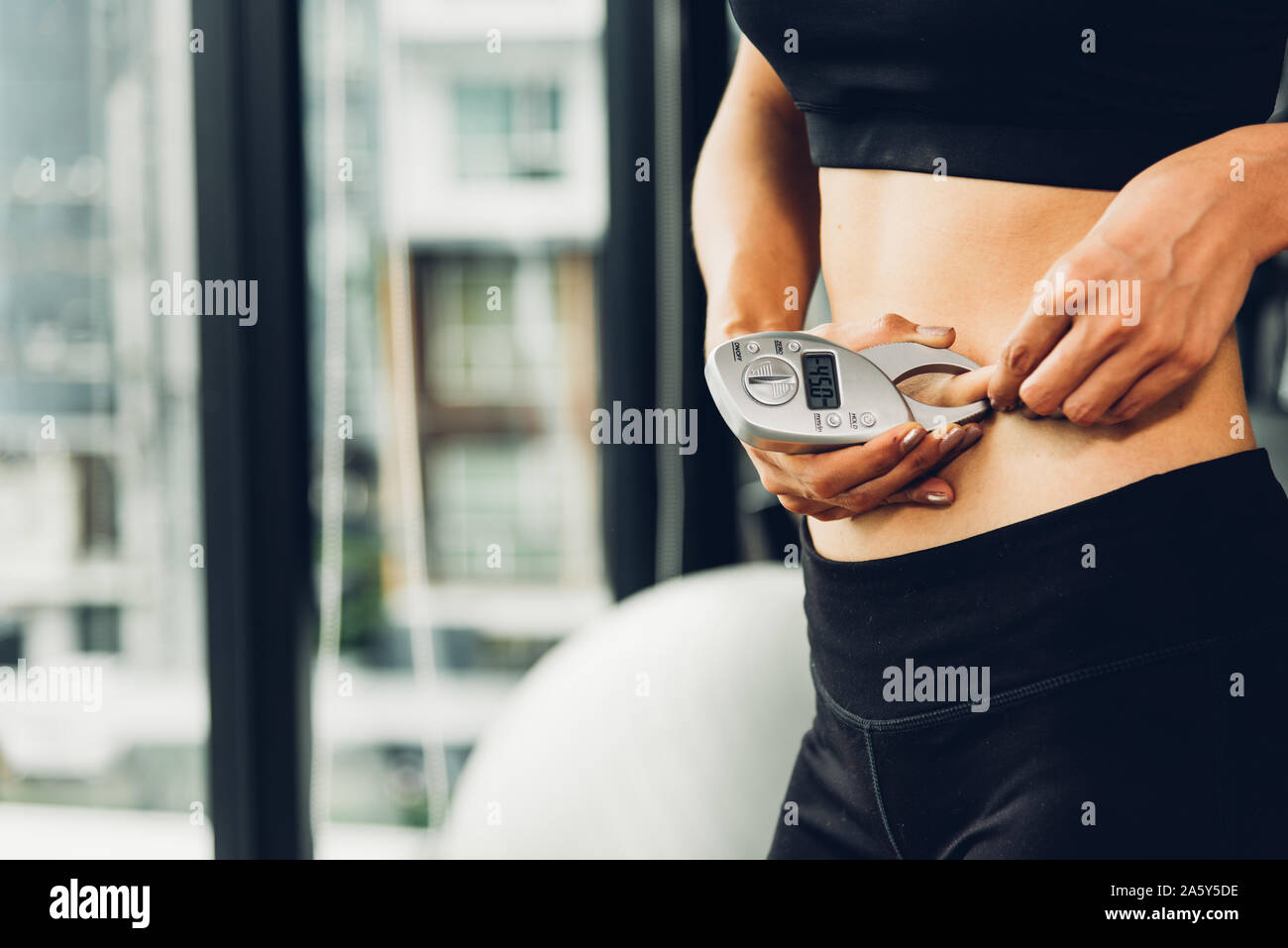 Beautiful woman using caliper fat measure after exercise workout out at fitness GYM Stock Photo