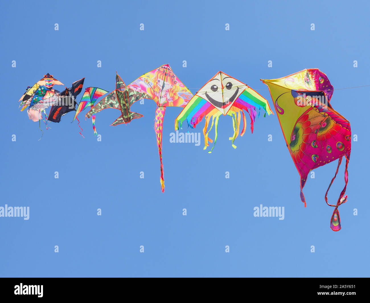 Bright, colorful kites flying in the background of the blue sky. A kite is a collection of tether-coupled wing sets. Childhood game. Leisure activity. Stock Photo