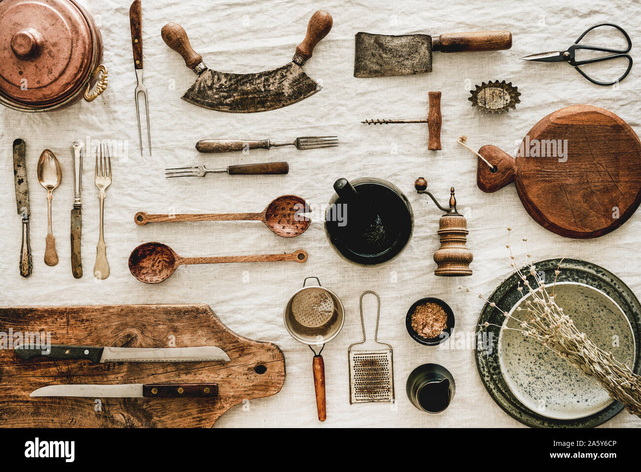 Various kitchen utensils and tablewear over rustic linen tablecloth Stock Photo