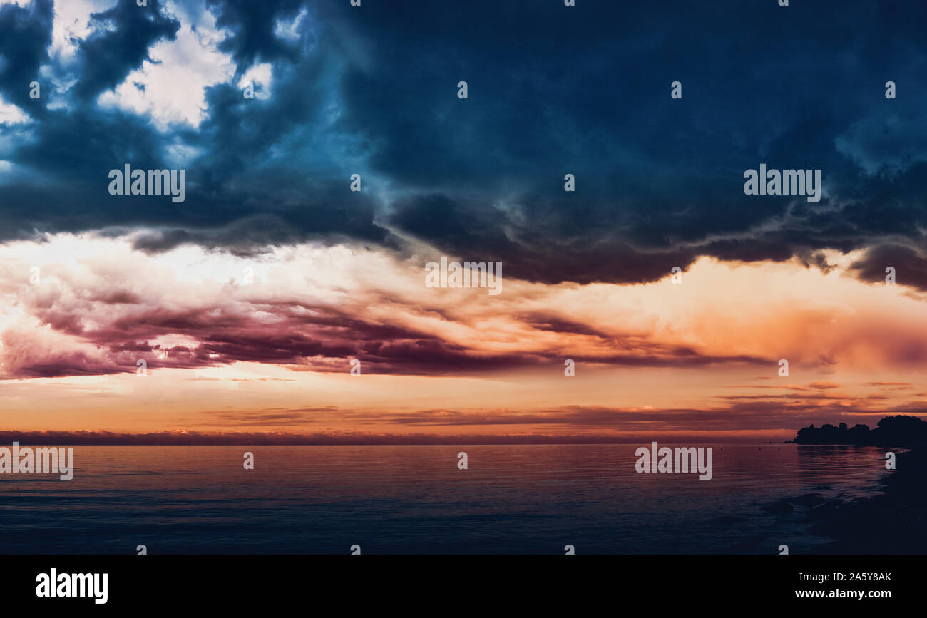 Dramatic light through the clouds against the backdrop of an exciting, stormy stormy sky at sunset, dawn. Hatching in water panorama, natural composit Stock Photo