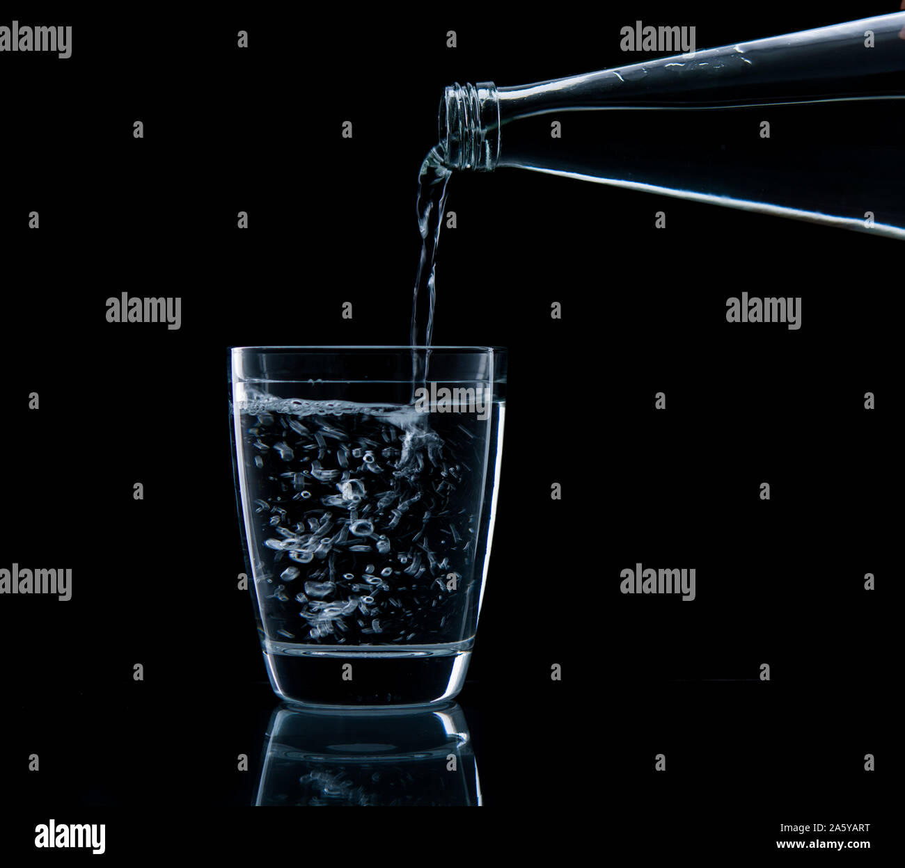 Pouring water on glass on over black background Stock Photo - Alamy