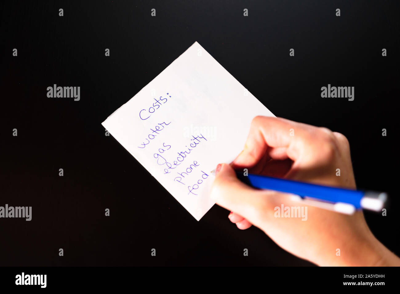 Writing on sticky note list of costs. Text with costs on paper Stock