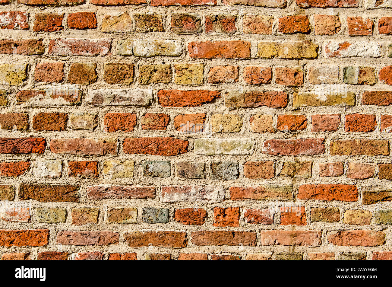 Section of a masonry wall with bricks in a large variety of colors, from red and brown to yellow and white and even blue Stock Photo