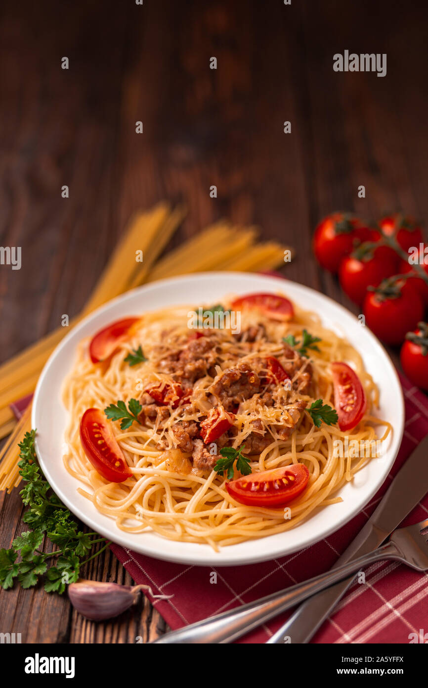 Pasta bolognese with tomato sauce and minced meat, grated parmesan cheese and fresh parsley - homemade healthy italian pasta on rustic background Stock Photo