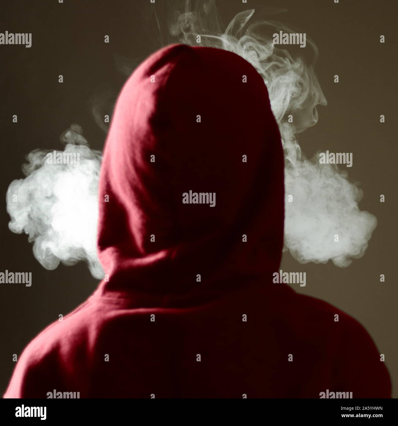 Young male in red hoodie vaping smoking, exhales thick vapor, isolated rear view Stock Photo