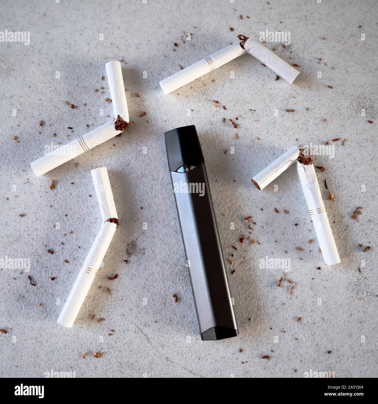 Single vape pen type electronic cigarette as smoking alternative with broken cigarettes and scattered tobacco on white textured background isolated Stock Photo