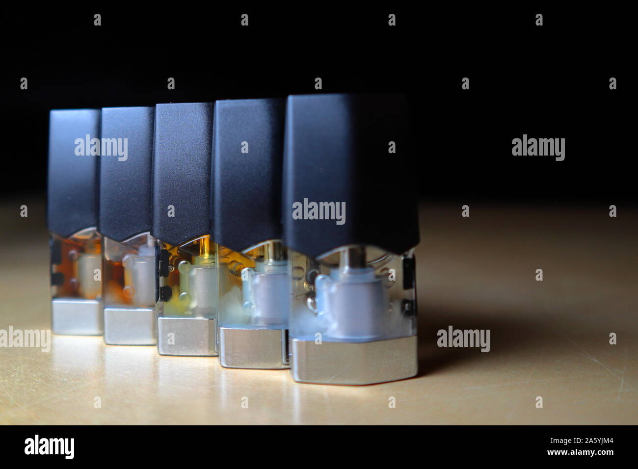 e-juice vape refill pods with liquids of different shades of orange arranged to form a gradient, isolated close up Stock Photo