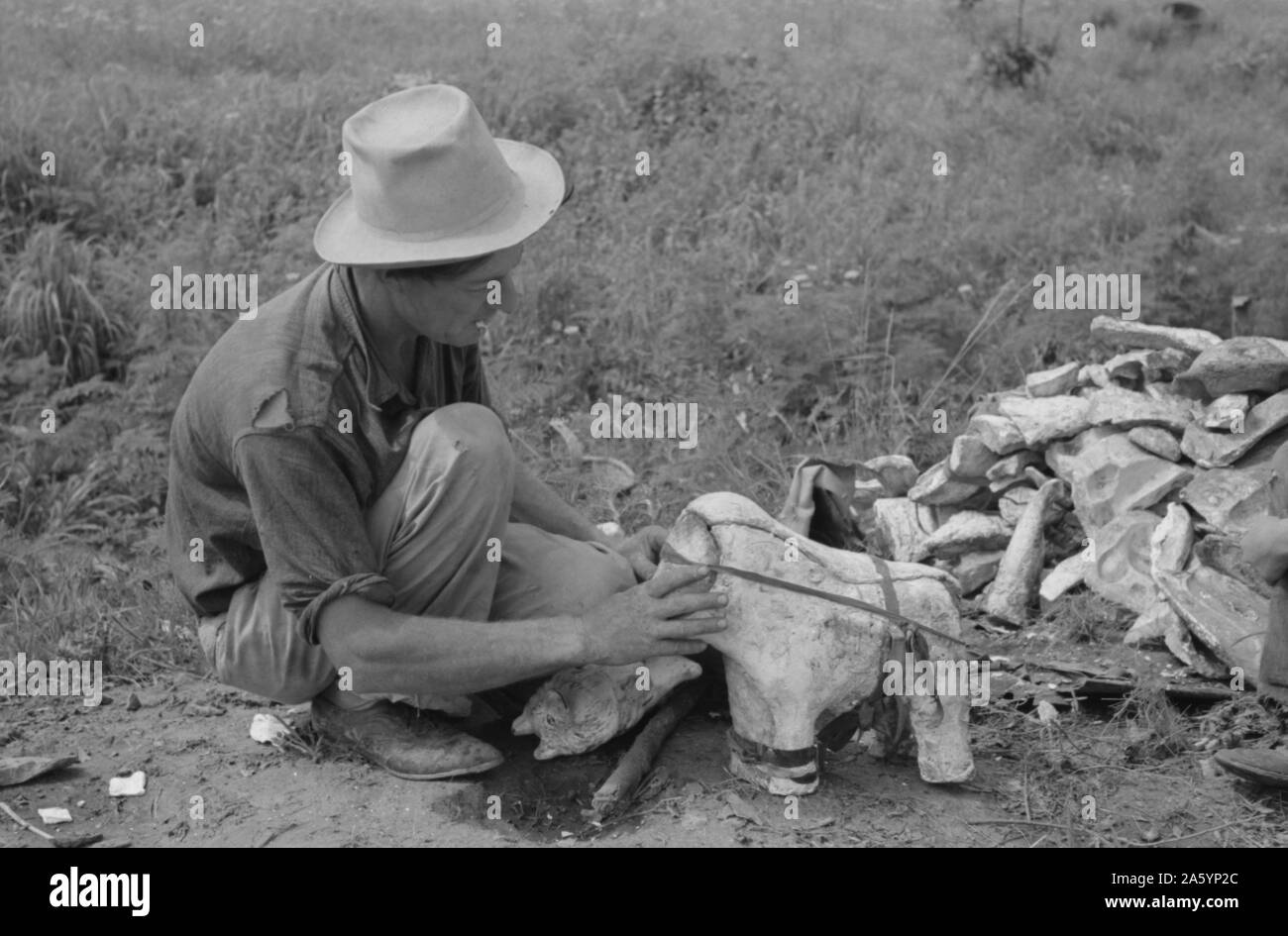 Itinerant statue maker putting together the pieces of a mould for one of his statues. He had been at one time an oil field worker. He said that the WPA (Work Projects Administration) had reduced the possibility of the man on the road getting a job. He said he believed he could farm if he could get a chance. Near Spiro, Oklahoma by Russell lee, 1903-1986, Stock Photo