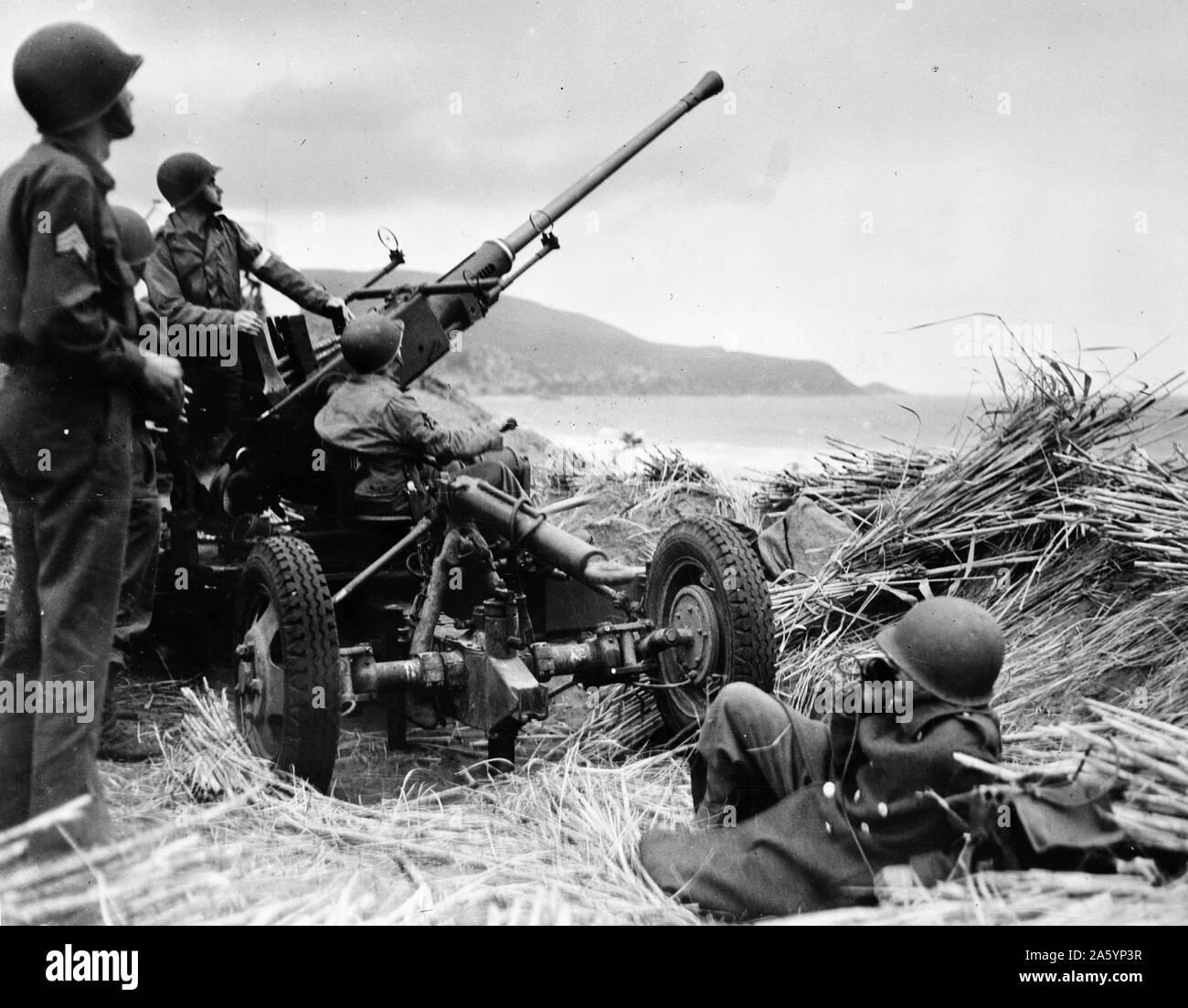 Anti-aircraft bofors gun in at position on a mound overlooking the beach in Algeria, with a United States anti-aircraft artillery crew in position 1943 . Stock Photo